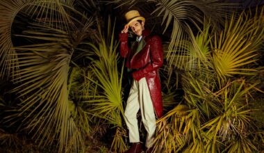 A ringmaster stands between palm fronds