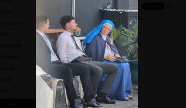 A photo of a nun sitting next to a two men wearing suits,