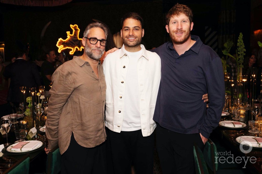photo of three men in button-down shirts posing together in a restaurant next to a table with place settings