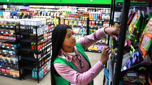 Sales associate Aaliyahna McDonald stocks shelves at the Go Grocer mini-market in Fort Lauderdale's Flagler Village on Tuesday, March 31, 2026. (Carline Jean/South Florida Sun Sentinel)