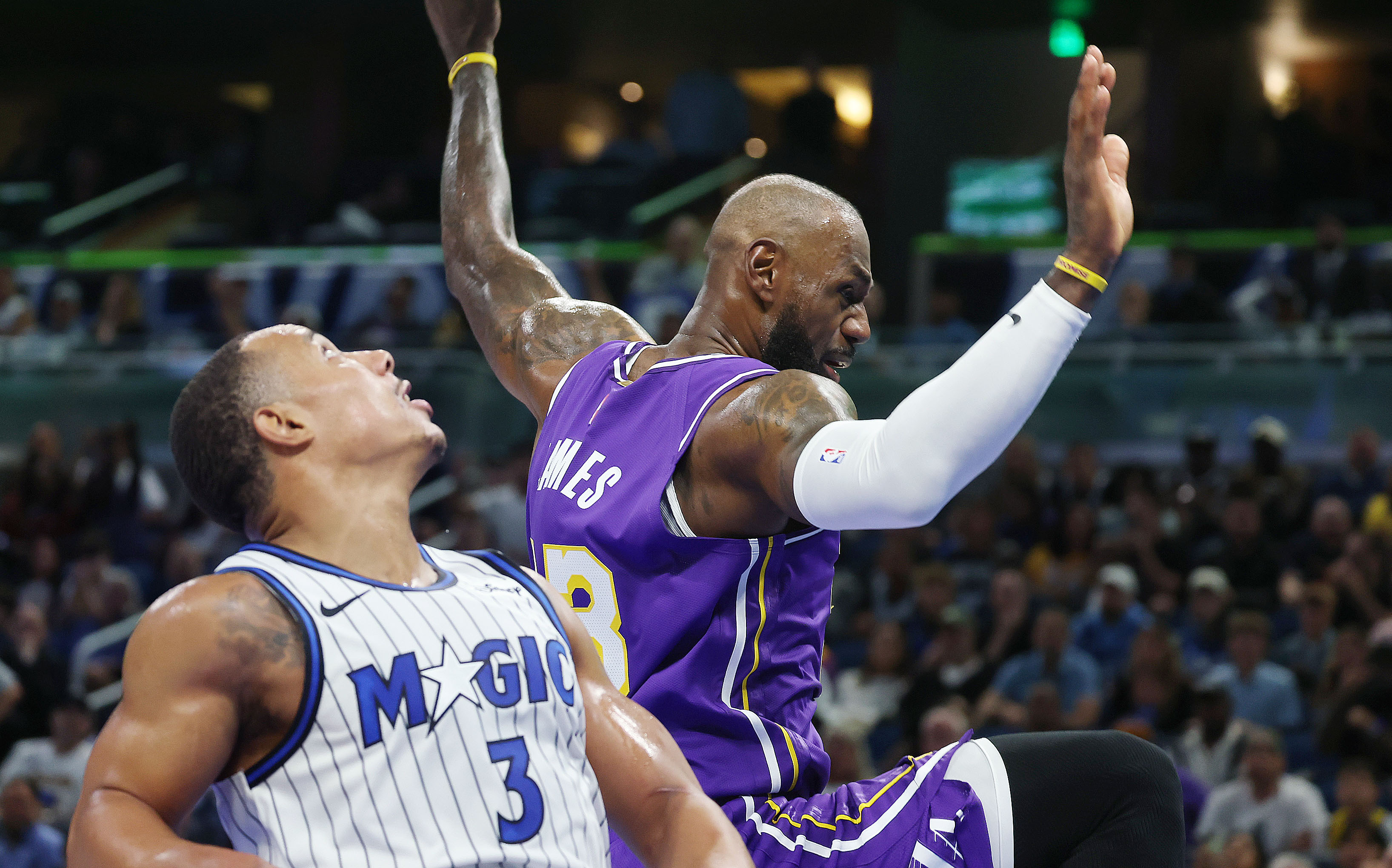LA forward LeBron James (top) falls beside Orlando guard Desmond...