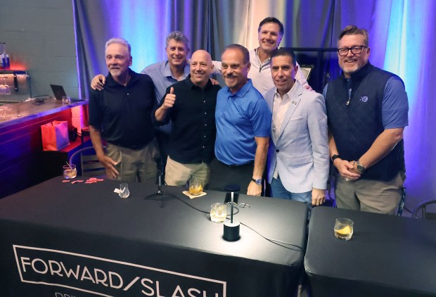 The sports experts gather for a group photo following a discussion about sports in Central Florida at Forward/Slash Distillery & Blending House in Winter Park on Wednesday, March 25, 2026. Sentinel columnist Mike Bianchi was joined by former colleagues Brian Schmitz and George Diaz and Orlando sports radio legend Marc Daniels to talk about the evolution of Orlando's pro, college and amateur sports. Jason Siegel, the president and CEO of Greater Orlando Sports Commission, and Steve Hogan, CEO for Florida Citrus Sports, joined the conversation to discuss the area's sports scene and its future. Pictured from left to right are: Brian Schmitz, Roger Simmons, Mike Bianchi, George Diaz, Steve Hogan, Mark Daniels, and Jason Siegel. (Stephen M. Dowell/Orlando Sentinel)