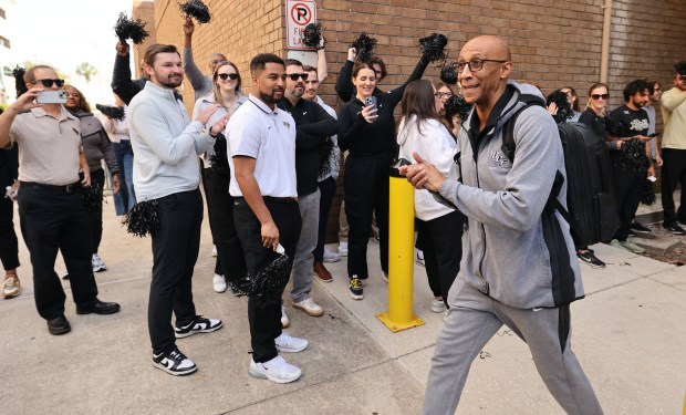 UCF head coach Johnny Dawkins smiles during a sendoff greeting as he walks out to board a bus outside Addition Financial Arena on Wednesday afternoon, March 18, 2026. The basketball team is headed to Philadelphia for an appearance in the NCAA Basketball tournament. (Stephen M. Dowell/Orlando Sentinel)