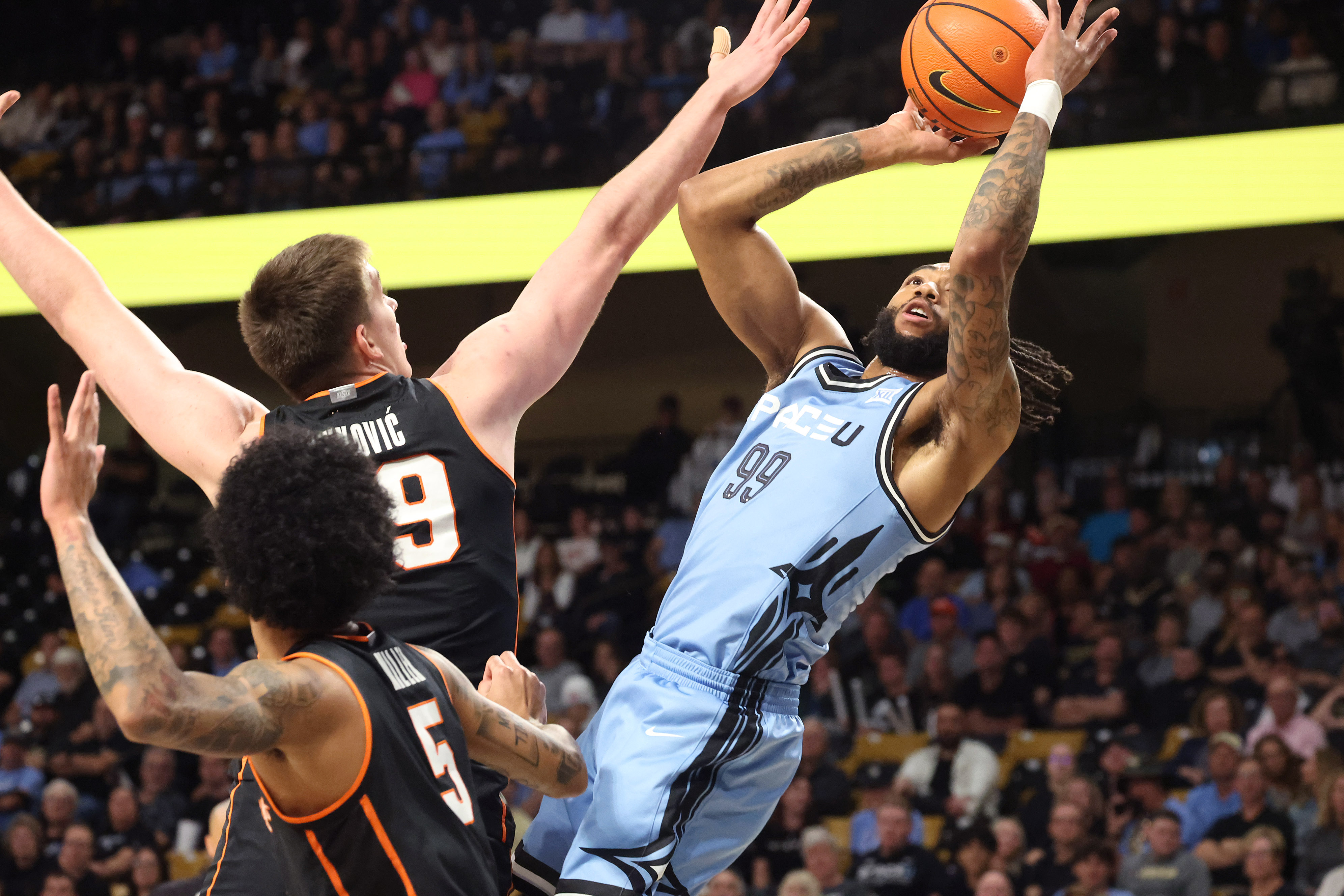 UCF forward Jordan Burks (99) scores past Oklahoma State defenders...