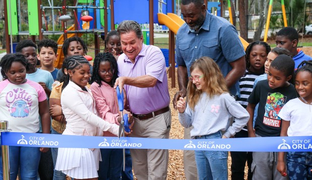 District 3 City of Orlando Commissioner Roger Chapin gets help from Rolling Hills Elementary School fourth-graders cutting the ribbon during the dedication ceremony for the renovation of the playground at Signal Hill Park in Pine Hills, Tuesday, March 3, 2026. The renovation is part of the city's Families, Parks and Recreation Department plan to upgrade 11 parks over the next two years. (Joe Burbank/Orlando Sentinel)