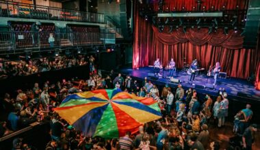 Photo of a concert with people holding a colorful fabric in the middle of the venue