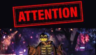 A photo showing the word attention in big red letters underneath a pumpkin scarecrow at Universal Halloween Horror Nights.