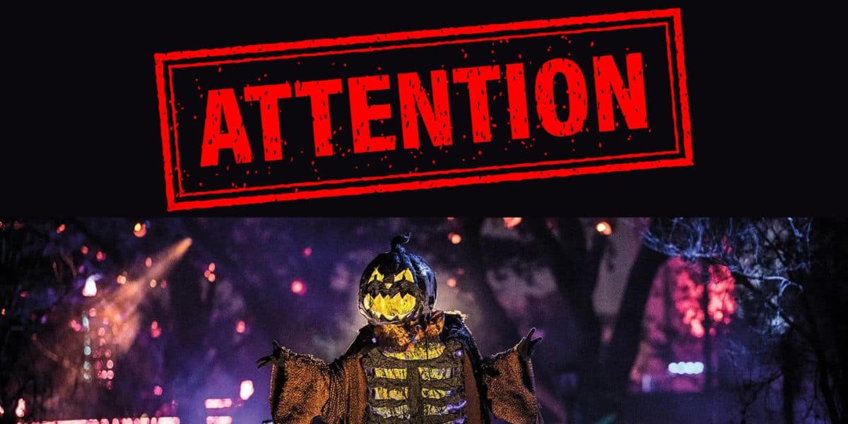A photo showing the word attention in big red letters underneath a pumpkin scarecrow at Universal Halloween Horror Nights
