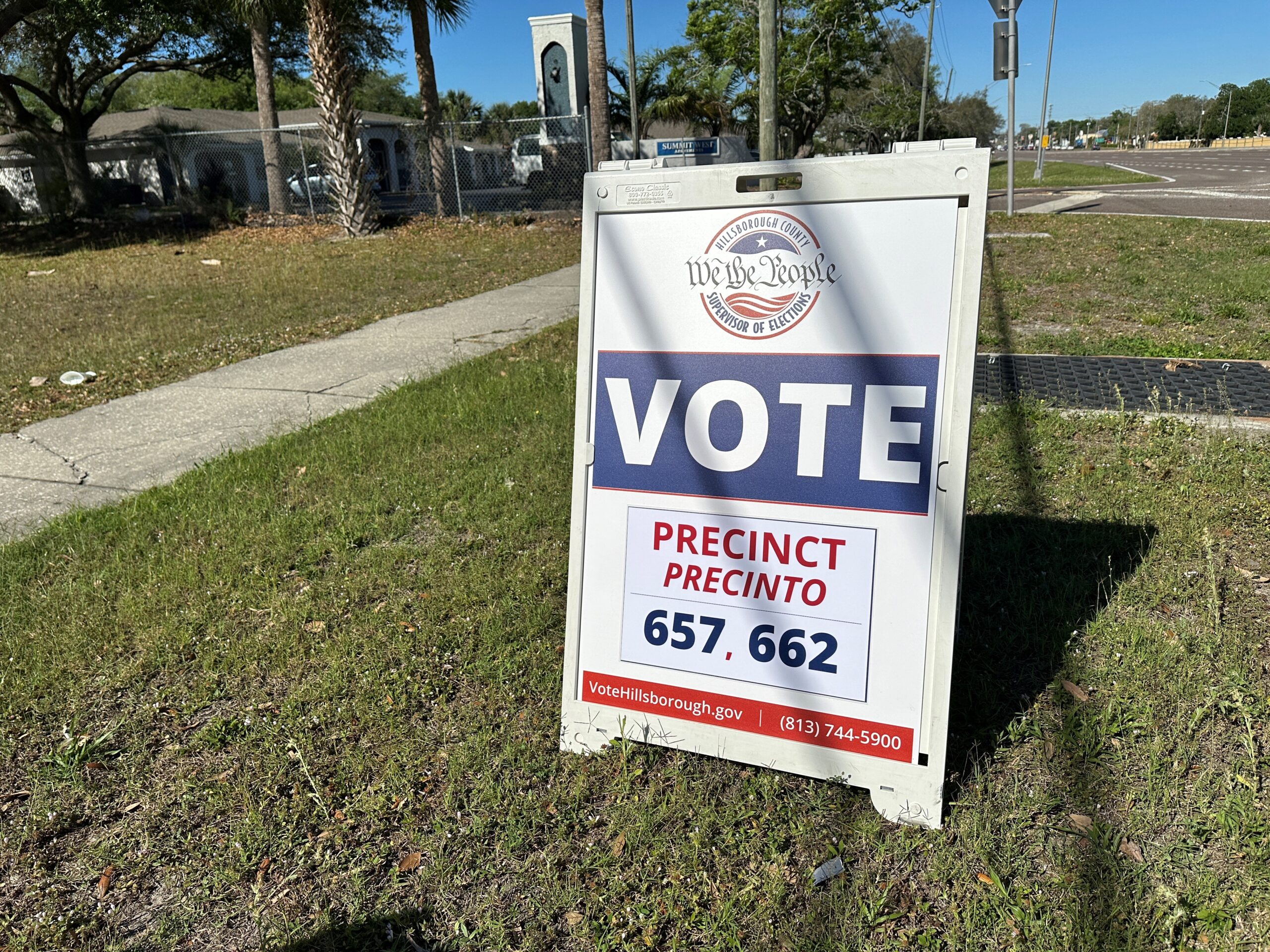 A white barrier stands in a grassy field that says "We The People" and "Vote." Election