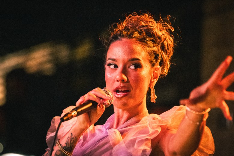 Songwriter Betty Dawl performing as Eemmyy at Crowbar in Ybor City; she wears a ruffled pink top and sings into a microphone during a Women's Day concert.