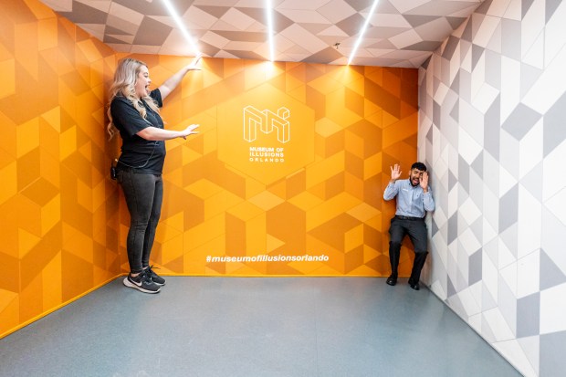 Museum of Illusions staff Dayna McNally, left, and Isaac Cabrera showcase an optical illusion at Icon Park in Orlando on March 29.