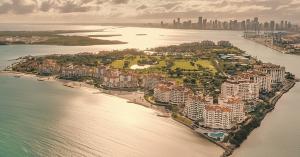 Aerial view of Fisher Island, Miami, and Miami skyline, at sunset, featuring deep-water access for superyachts, represented by LIME Yacht Brokerage.