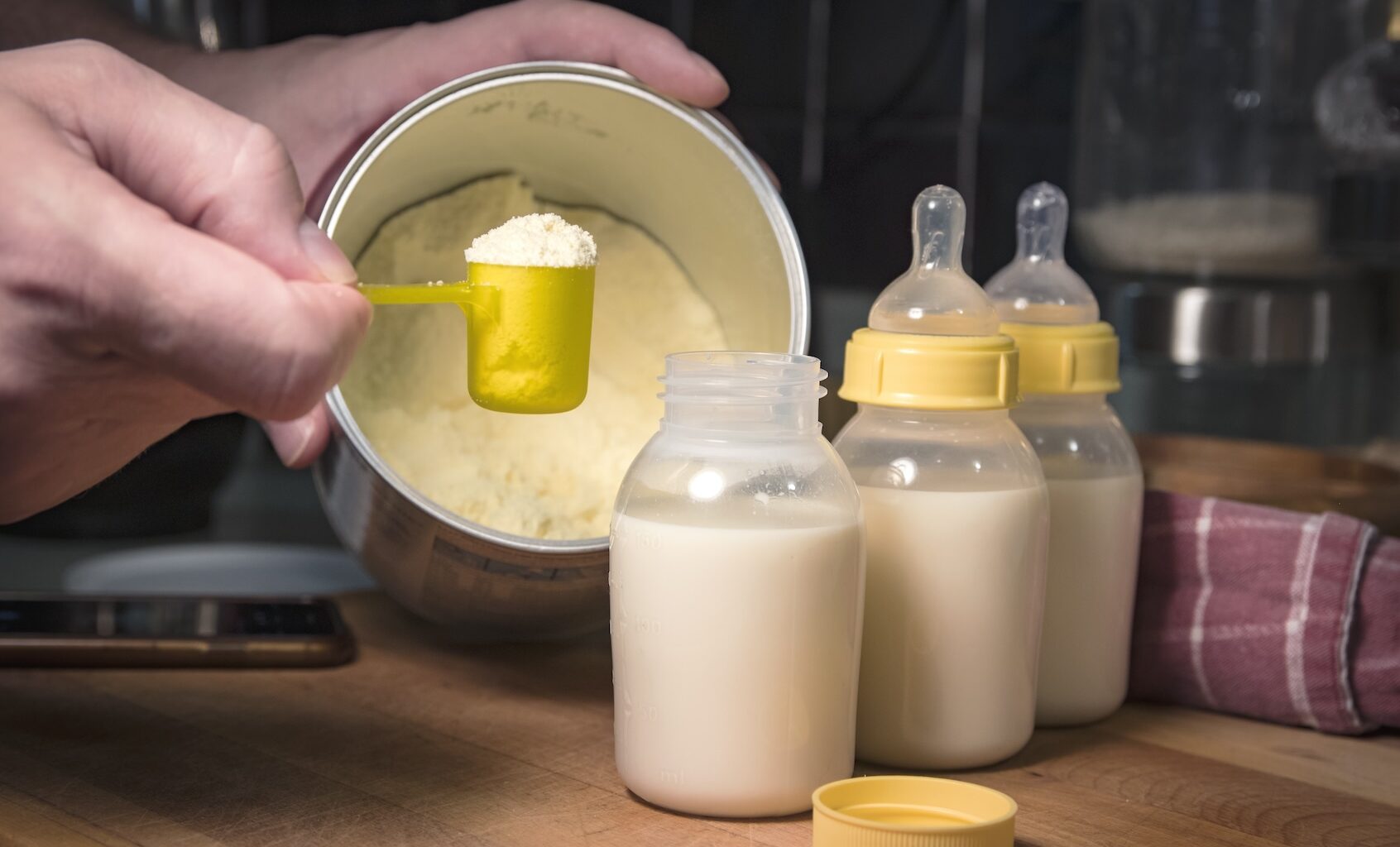 Hand holding scoop of powdered baby formula. (Benjamin Clapp / Getty Images)