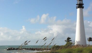 photo of a white lighthouse towering over dunes on the beach
