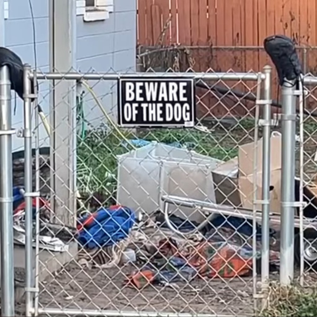 A fence with a dog warning sign on it.