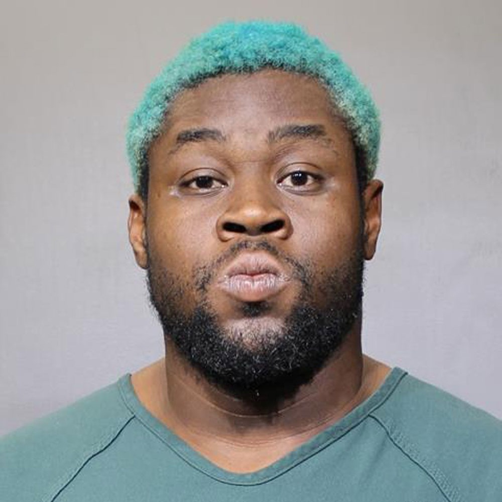 A mugshot of a man with blue hair.
