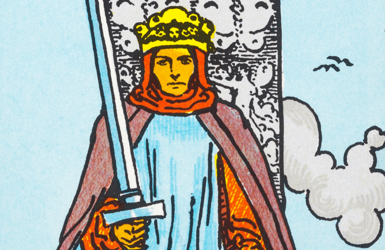 A close-up illustration of the King of Swords from the Rider-Waite Tarot deck. A figure with a stern expression wears a yellow crown and a red hood under a blue tunic and purple cape. They hold a large silver sword upright in their right hand against a pale blue sky with a single cloud and soaring birds.