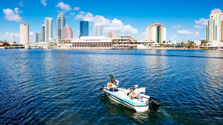 Boaters in a small fishing vessel offshore Tampa with the skyline and Tampa Convention Center in the background
