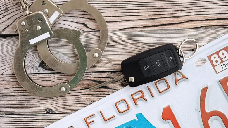 Handcuffs and car key next to Florida license plate