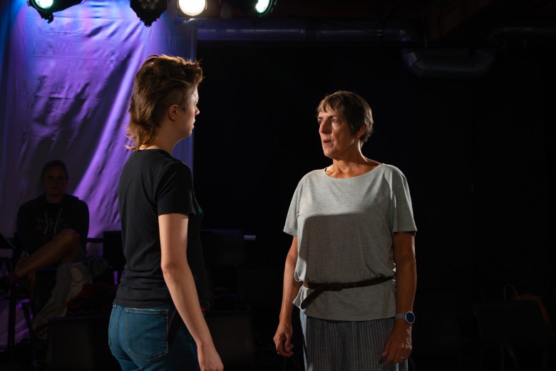 Two actors engaging in a dramatic scene on a dimly lit stage during a rehearsal of The Studio@620's 'Julius Caesar.'