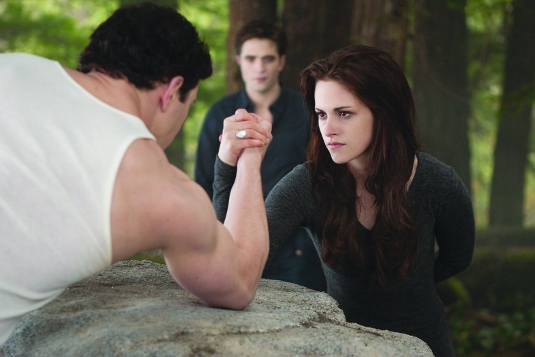 A shot from the Twilight Saga of Kristen Stewart arm wrestling a man as Robert Pattinson watches