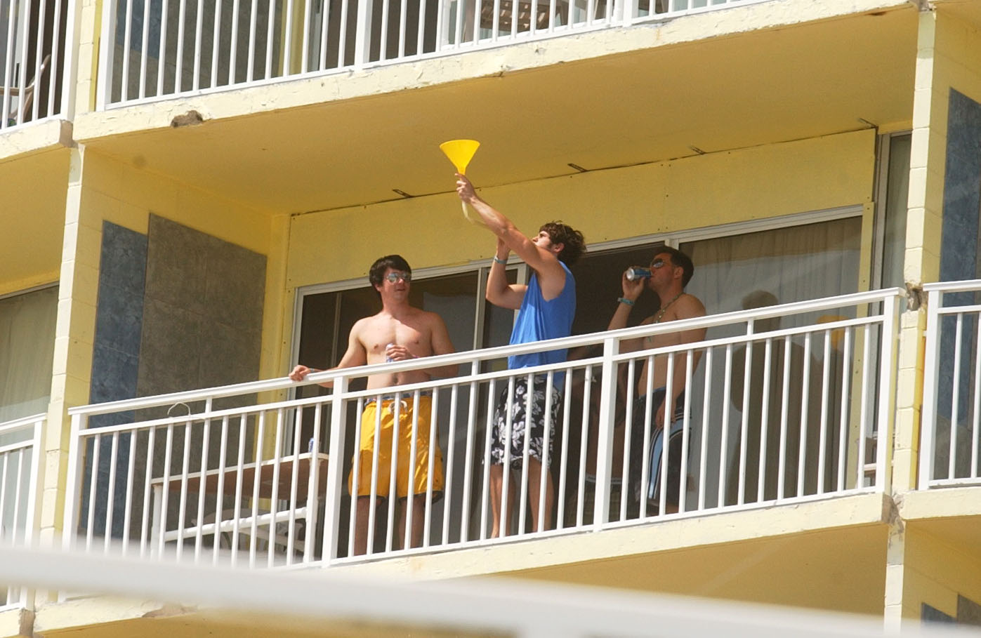 Springbreakers with a beer bong on a balcony of the...