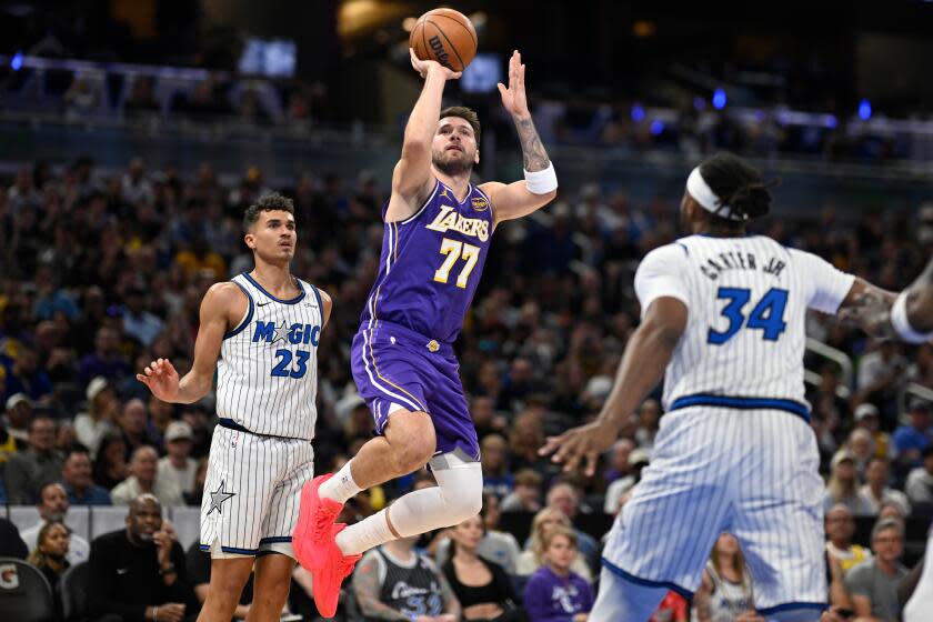 Los Angeles Lakers guard Luka Doncic (77) goes up to shoot between Orlando Magic.