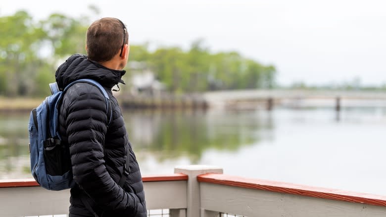 man with backpack looking at view of bridge