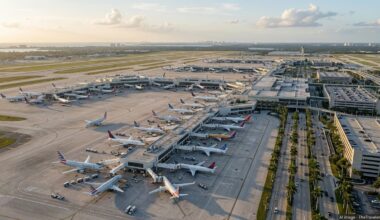 Aerial golden hour view of a busy Florida airport with planes at palm-lined terminals.