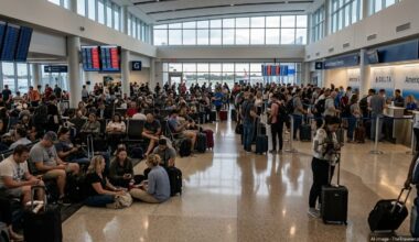 Crowded Fort Lauderdale airport terminal with stranded passengers and delayed flights on departure boards.