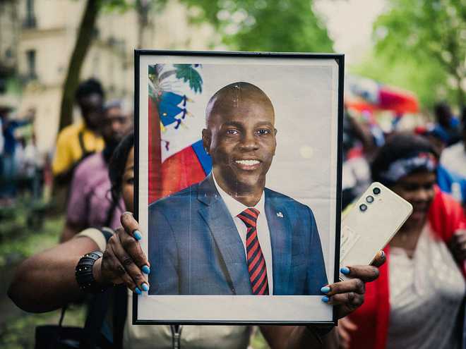 A person with a portrait of Jovenel Moise former president of the Republic of Haiti during a demonstration for peace in Haiti in Paris France May 3, 2025. (Photo by Bastien Ohier / Hans Lucas / Hans Lucas via AFP) (Photo by BASTIEN OHIER/Hans Lucas/AFP via Getty Images)