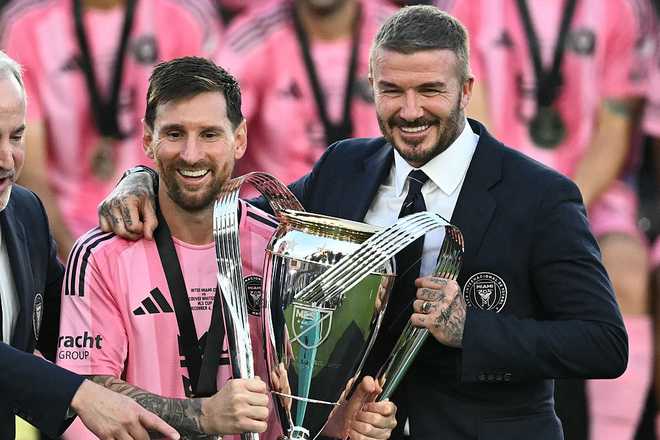 TOPSHOT - Inter Miami's Argentine forward #10 Lionel Messi (L) poses with the trophy next to the team's owner David Beckham (R) after winning the Major League Soccer (MLS) Cup final between Inter Miami and the Vancouver Whitecaps at Chase Stadium in Fort Lauderdale, Florida, on December 6, 2025. (Photo by CHANDAN KHANNA / AFP via Getty Images)