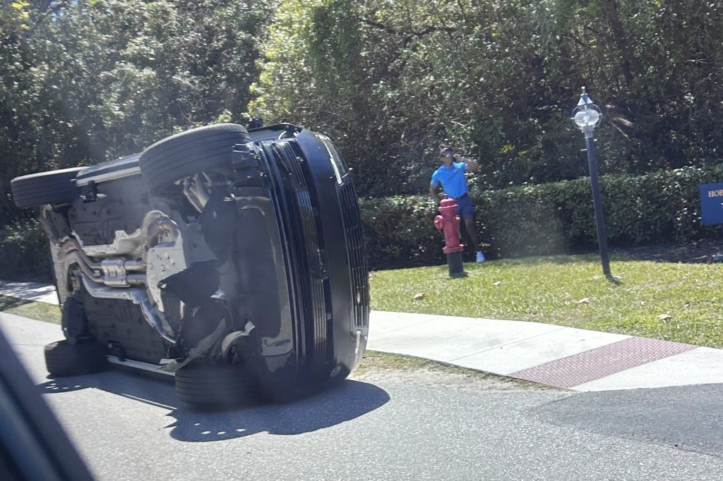 Tiger Woods standing by his overturned vehicle after a crash.