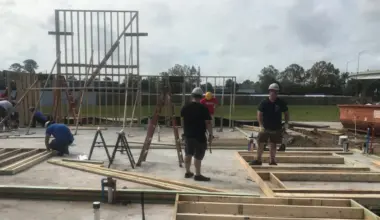 Volunteers work on laying a home's foundation and putting up walls.
