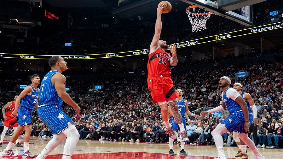 Toronto Raptors forward Sandro Mamukelashvili (54) scores between the Orlando Magic defense during first half NBA action in Toronto on Sunday, March 29, 2026. (Frank Gunn/The Canadian Press via AP)