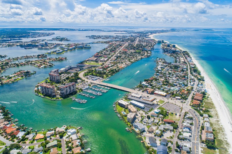 Aerial view of St. Pete Beach, Florida, showing turquoise Gulf waters, white sand coastline, and luxury beachfront resorts under a clear blue sky.