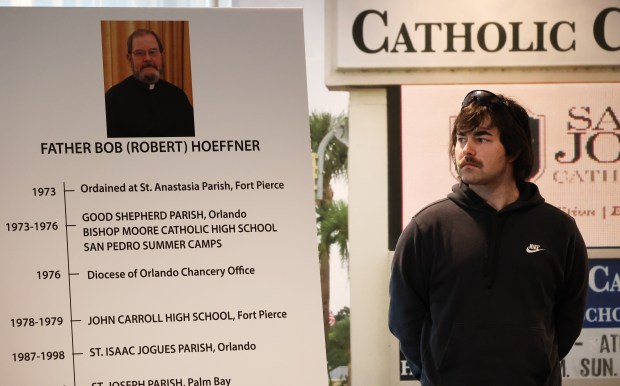 Shawn Teuber looks at a poster outlining the career of father Robert "Bob" Hoeffner, during a press conference after his attorney Jeff Herman filed a lawsuit against St. Joseph Catholic Church and School, on Friday, May 30, 2025. Plaintiffs are finding that under Florida law, many of their legal claims are time-barred. (Ricardo Ramirez Buxeda/Orlando Sentinel)