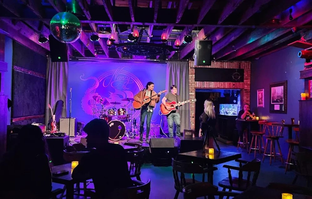 a stage and a performer playing a guitar at a bar in Miami called Bar Nancy that has since closed down