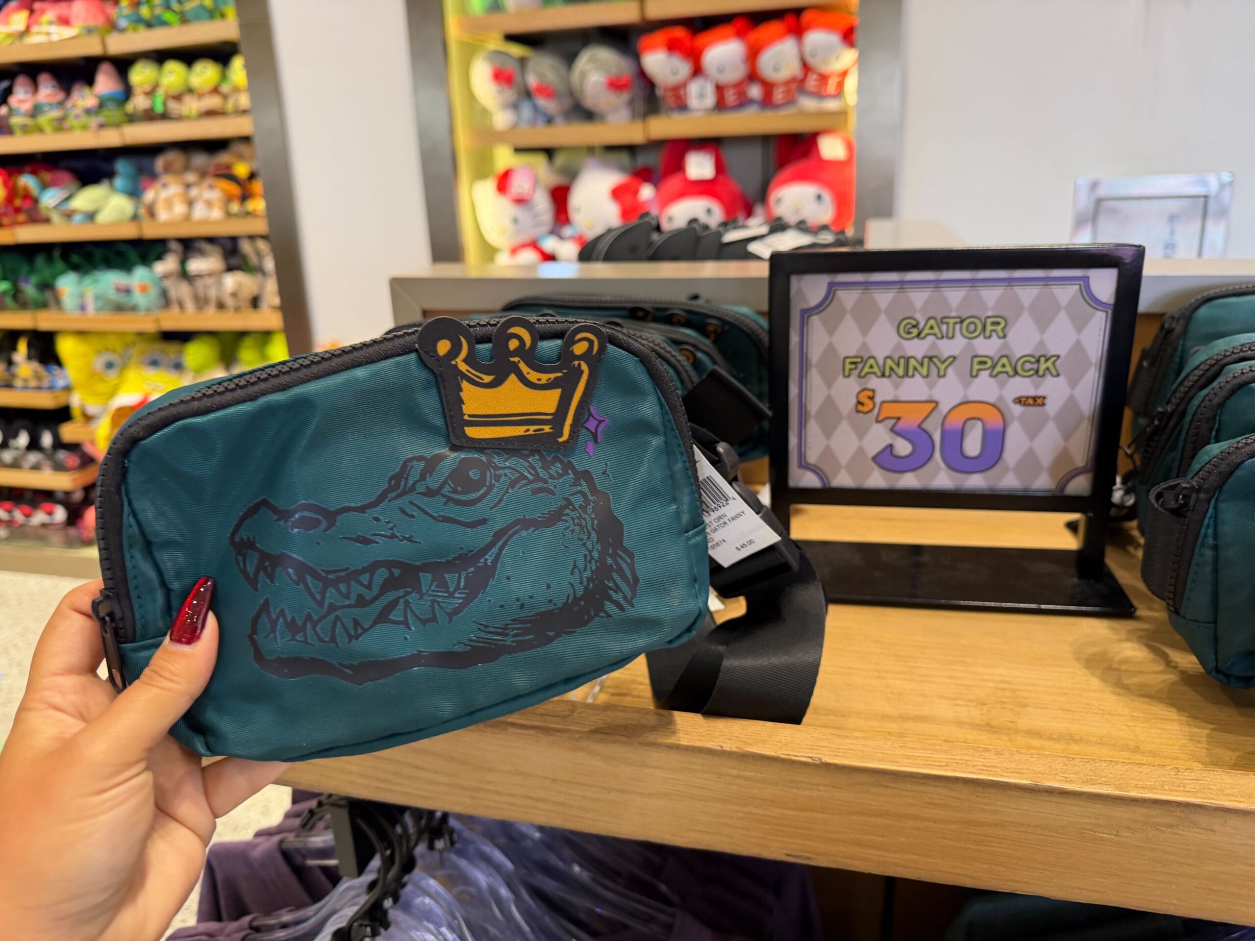 This dark green fanny pack has a black outline of King Gator's head with a 3D yellow crown applique. The zipper and strap are black as well.