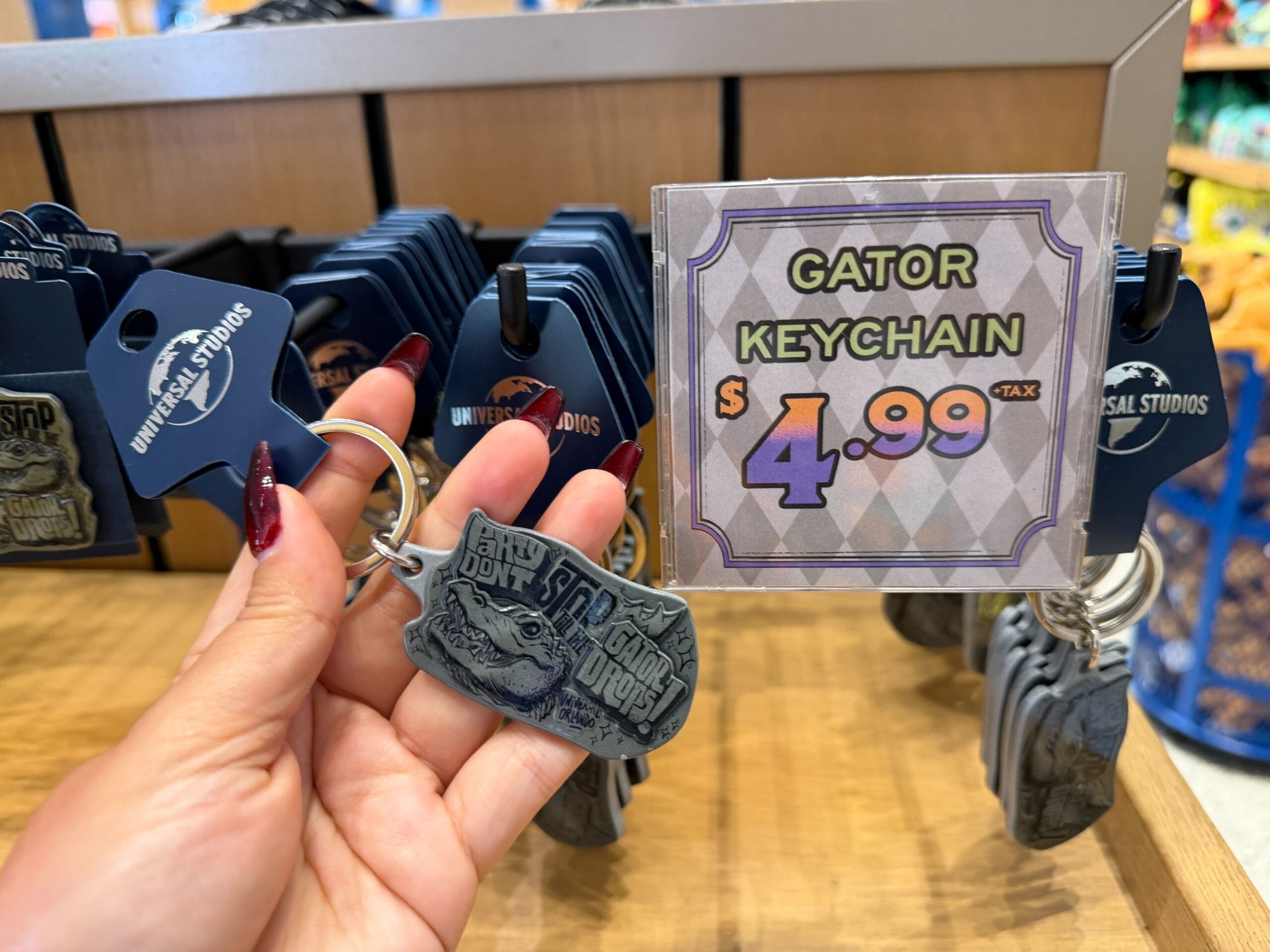 This green-gray keychain is decorated with the head of King Gator, one of the mascots of the Mardi Gras season at Universal Orlando. The keychain also has the text, "Party don't stop till the gator drops!"