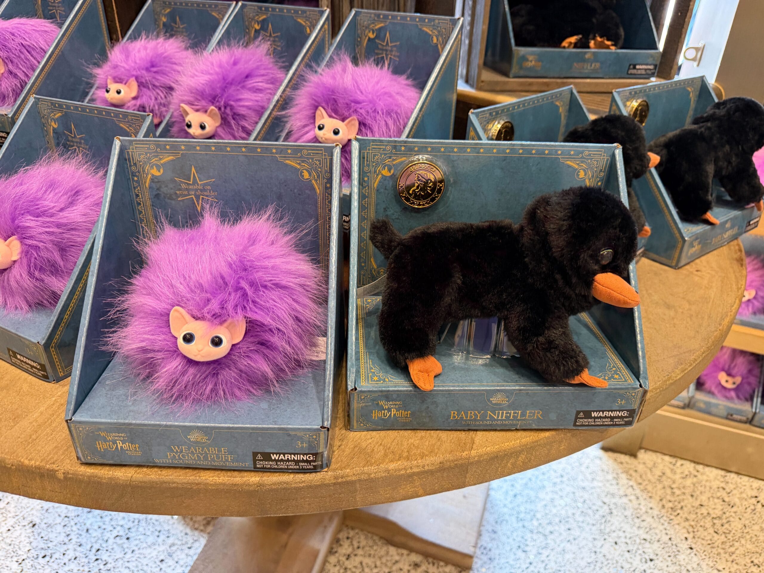 The Pygmy Puffs are covered in fluffy, purple fur, while the Nifflers have sleek, black fur.