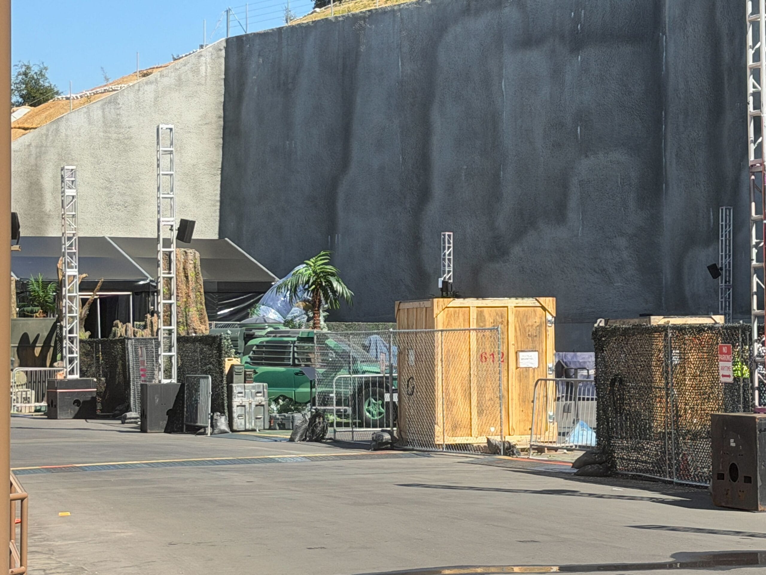 In addition to the T. rex, Spinosaurus, and InGen truck, there is now a green camouflage car, palm trees, rock features, and possibly more dinosaurs covered by tarps.