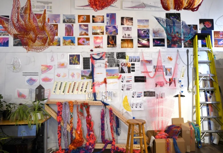 ehind the scenes in Janet Echelman's artist studio, showing concept sketches, mood boards, and colorful scale models of her large-scale aerial net sculptures