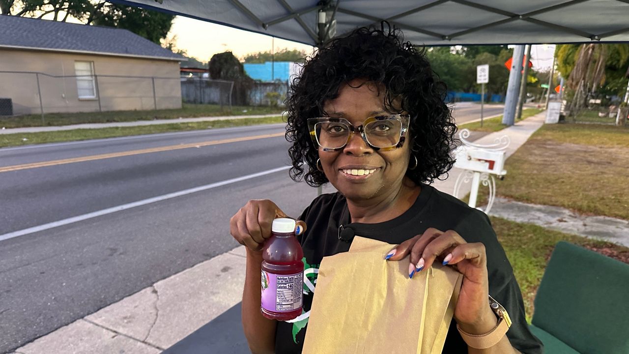 Diane Wingfield hands out snacks to school kids in front of Agape Church of God in Christ. (Spectrum News)