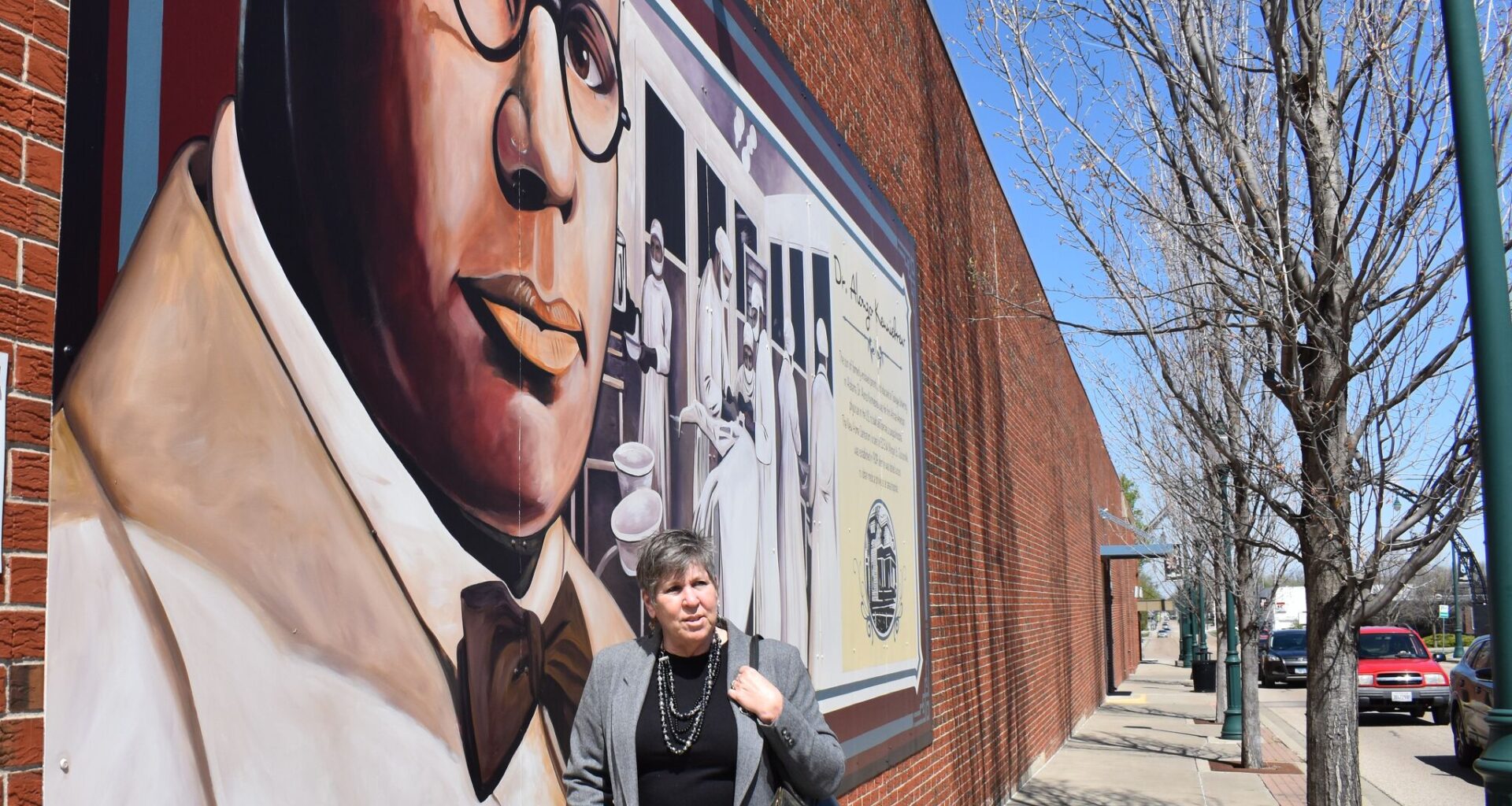 Judy Tighe stands in front of the mural Dr. Alonzo H. Kenniebrew on the side of the Lincoln Land Community College building on North Main Street, just off the downtown square. A new mural will be added to downtown's collection in coming months.