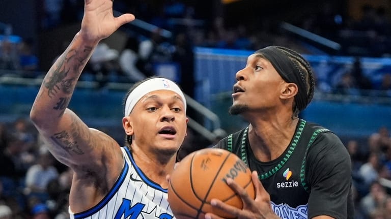 Minnesota Timberwolves forward Jaden McDaniels, right, shoots against Orlando Magic...