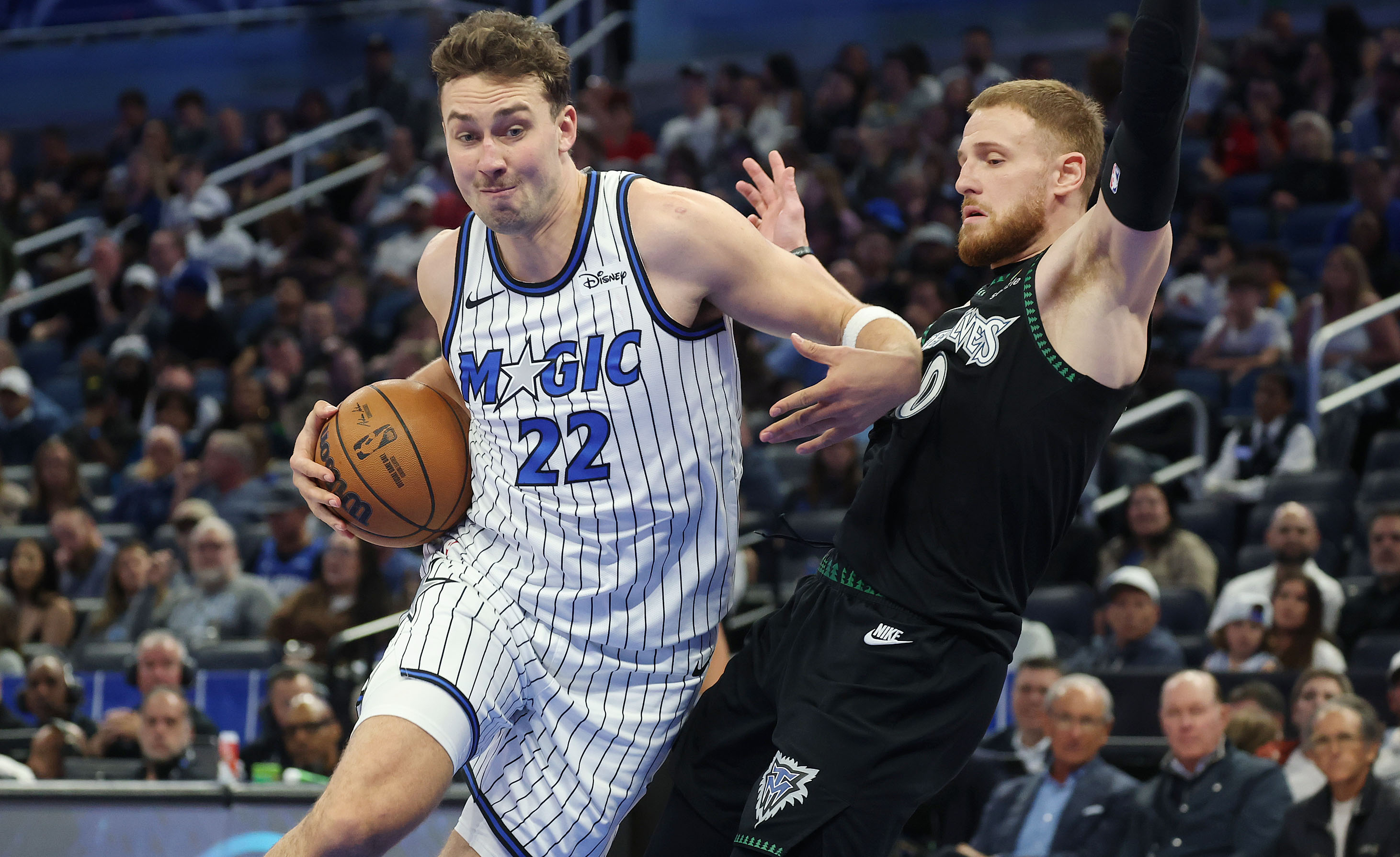 Magic forward Franz Wagner (22) shoves aside Timberwolves guard Donte DeVincenzo (0) during Wednesday's game at Kia Center. (Stephen M. Dowell/Orlando Sentinel)
