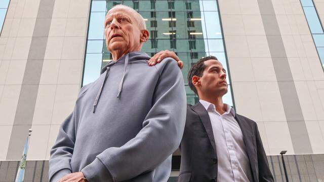 Pablo Langesfeld, left, who lost his daughter and son-in-law in the 2021 Champlain Towers collapse, stands with his son Martin, right, outside the Osvaldo N. Soto Miami-Dade Justice Center in Miami, Tuesday, April 7, 2026. Langesfeld, now battling advanced pancreatic cancer, is suing Oscar Health Insurance for denying coverage of a drug therapy his doctors recommend, underscoring broader struggles over access to treatment.