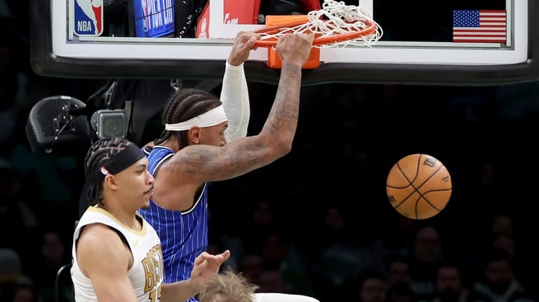 Orlando Magic forward Paolo Banchero, top right, dunks next to...