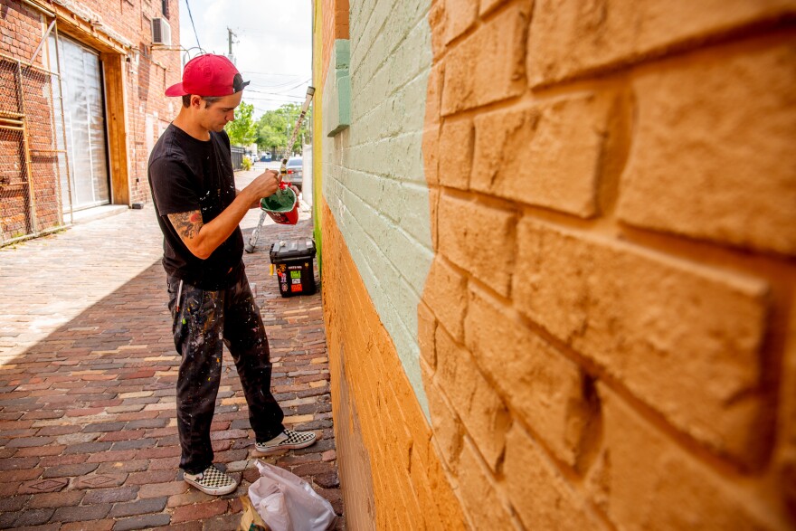 Dylan Perry, a Tampa artist, works on his first mural in the city. It's on a large brick wall on a building next to the Rialto Theatre near downtown Tampa.